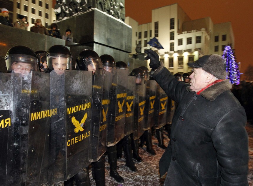 An opposition supporter makes the sign of the cross in front of riot policemen during a rally in central Minsk
