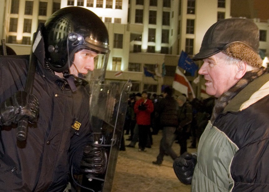 An opposition supporter and a riot policeman look at each other during a rally near the Parliament building in central Minsk