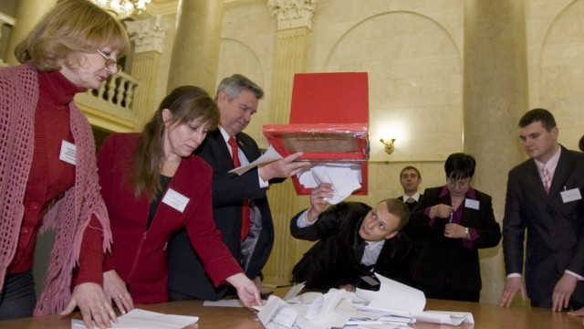 Members of local election committee empty a ballot box after polls closed at a polling station in Minsk