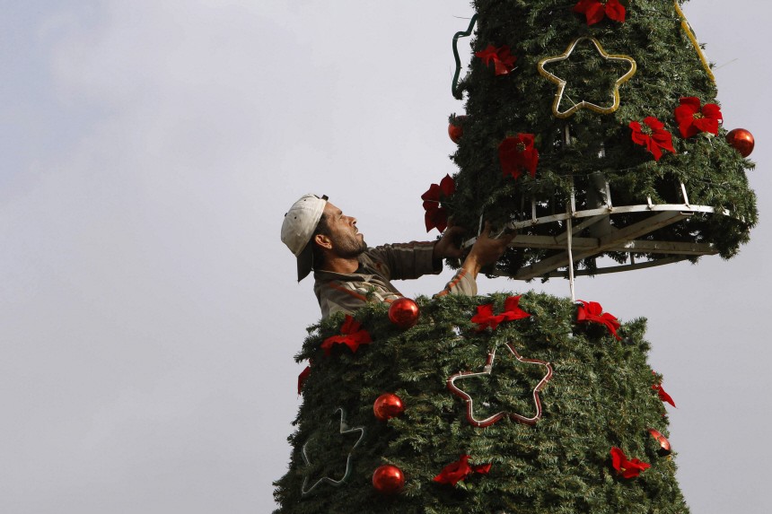 A worker adjusts the upper part of a Christmas tree that was lifted up by a crane in Sidon, southern Lebanon