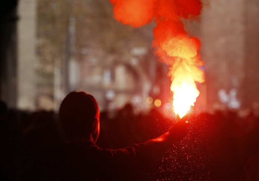 A student holds a lit  flare during a demonstration in Rome