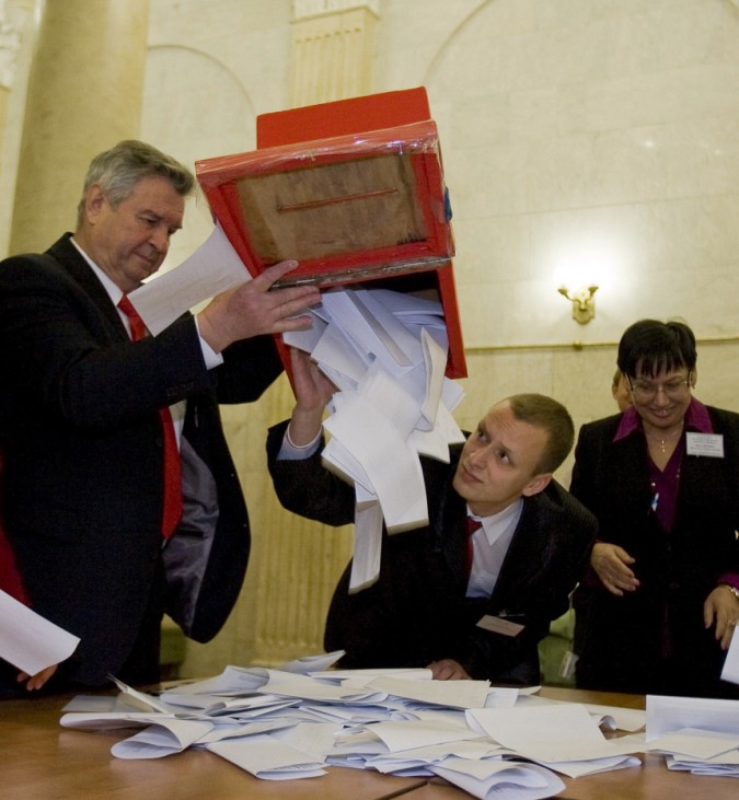 Members of local election committee empty a ballot box after polls closed at a polling station in Minsk