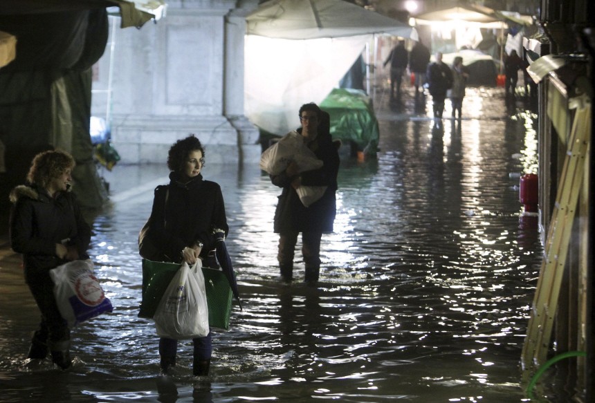 Women window shop as they walk on a flooded sidewalk in Venice