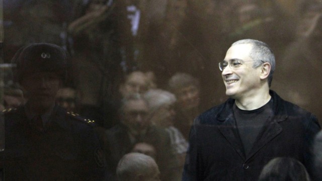 Jailed Russian former oil tycoon Khodorkovsky smiles as he stands in the defendants' cage before the start of a court session in Moscow