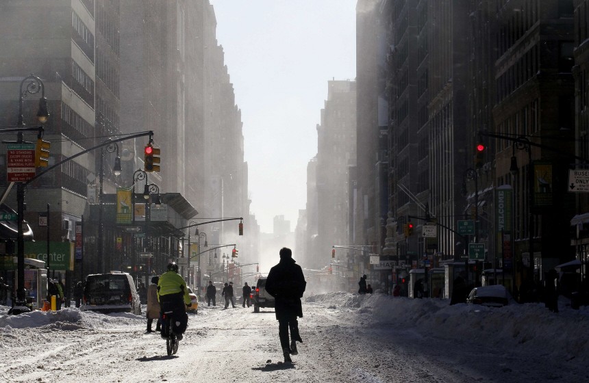 A man runs through the snow down the center of 7th Avenue in New York