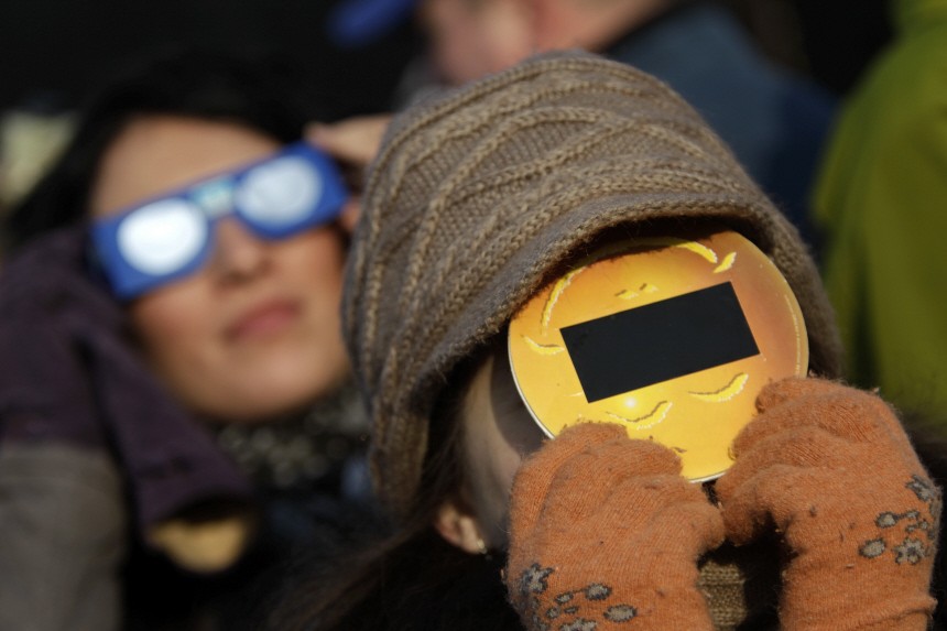 People wear protective eyewear as they look at a partial solar eclipse in Bucharest