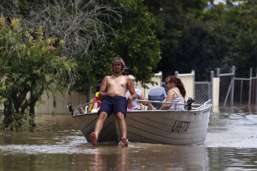 A man sits in the front of his boat as he navigates through floodwaters in Depot Hill in Rockhampton
