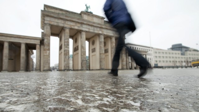 Glätte und Tauwetter in Deutschland: Ein Fußgänger wagt sich vor dem Brandenburger Tor in Berlin aufs Eis. In der Hauptstadt kam es am Donnerstag zu fast 500 Unfällen.
