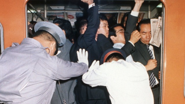 Personal schiebt Fahrgäste in Tokioter U-Bahn