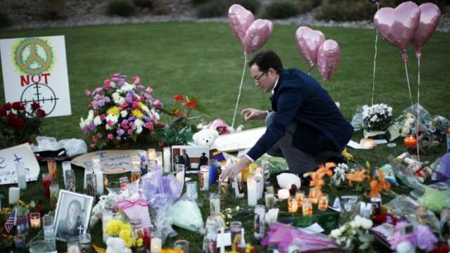 A man lights a candle at a memorial outside the hospital where victims of yesterday's shootings are recovering in Tucson