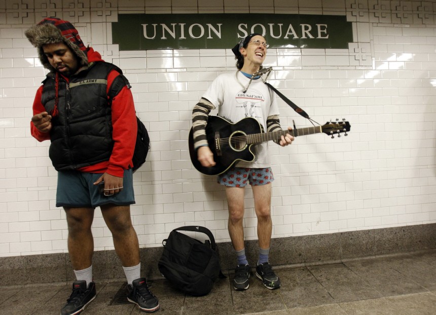 People taking part in the 10th Annual No Pants Subway Ride play guitar and dance at the Union Square subway station in New York City