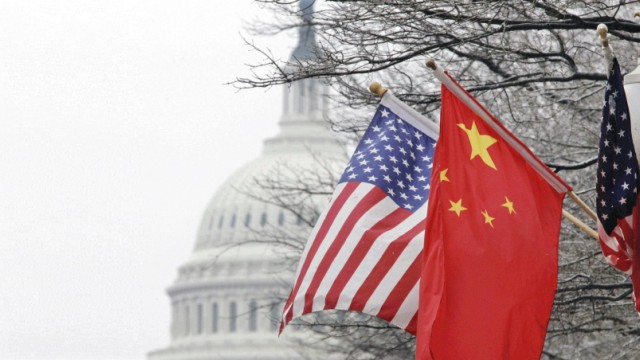 USA und China: Chinesische und amerikanische Flaggen an einem Laternenpfahl in Washington, im Hintergrund die Kuppel des Kapitols.