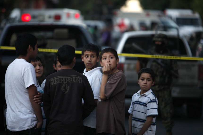 Children stand along the perimeter of a crime scene where five people were gunned down in Monterrey