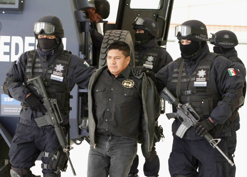 Federal police escort suspect Flavio Mendez Santiago during a news conference at the federal police headquarters in Mexico City
