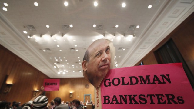A protestor holds a sign with a picture of Goldman Sachs's Blankfein during the testimony at a Senate Homeland Security and Governmental Affairs Investigations Subcommittee hearing on Capitol Hill in Washington