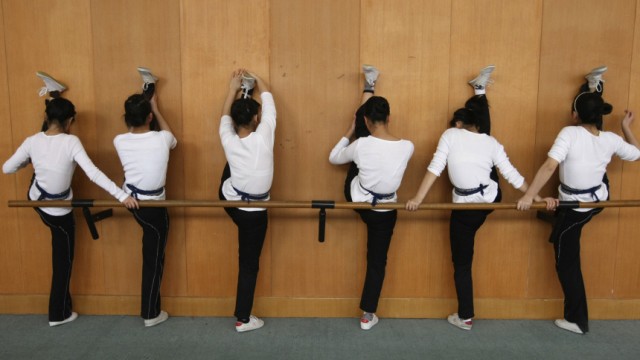 Students stretch against a wall during physical practice for Yueju opera at an art school in Hangzhou