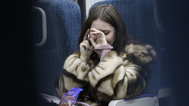 A woman cries, while talking on the phone to an acquaintance who is at Domodedovo airport, as she travels by train to the airport from Moscow