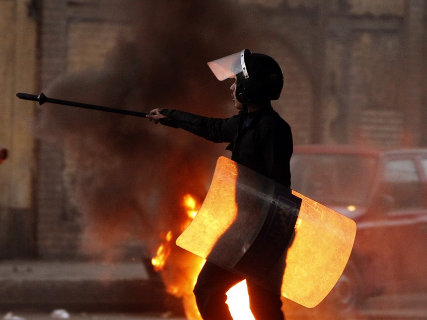 A riot policeman walks past burning tyres placed to form a barricade during clashes with protesters in Cairo