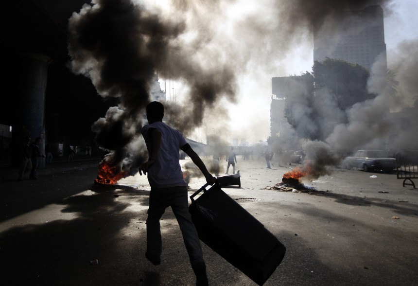 A protester runs in front of burning barricade during a protest in Cairo