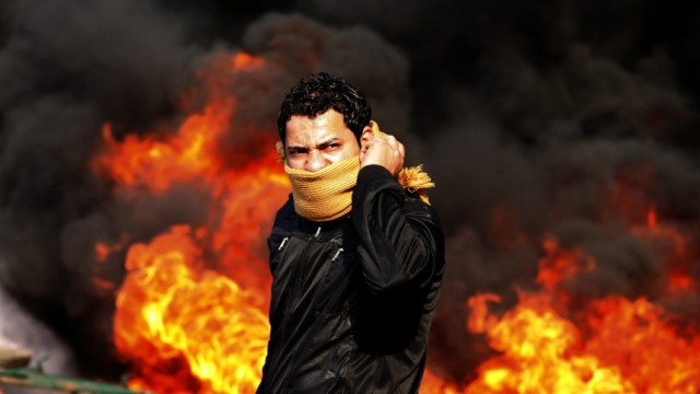 A protester stands in front of a burning barricade during a demonstration in Cairo