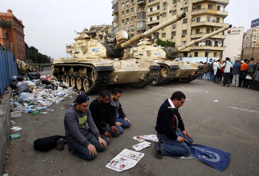 Protesters pray in front of Army tanks during a mass demonstration against the government in Tahrir Square in Cairo