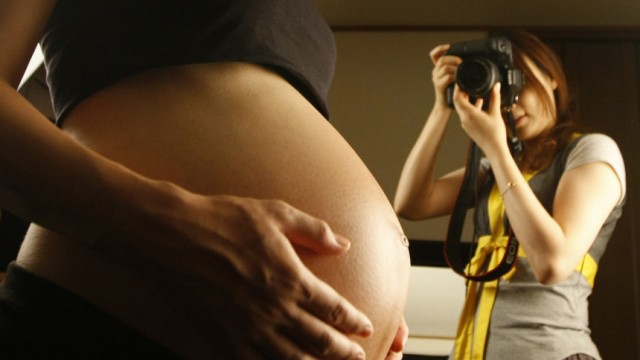 A pregnant woman poses with her bare belly at maternity photo studio 'Ixchel' in Tokyo
