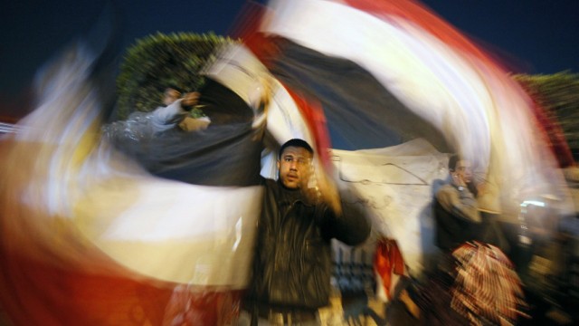 An Egyptian man waves Egyptian flags inside Tahrir Square after the announcement of Egyptian President Hosni Mubarak's resignation in Cairo
