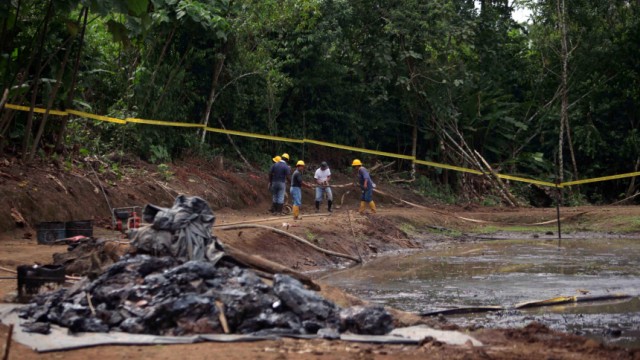 Ecuadorean workers clean up an oil waste pit owned by state petroleum company Petroecuador in Shushufindi