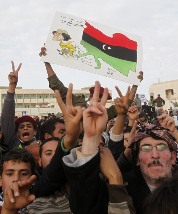 Protesters chant anti-government slogans while holding a banner depicting Libyan leader Muammar Gaddafi in Tobruk