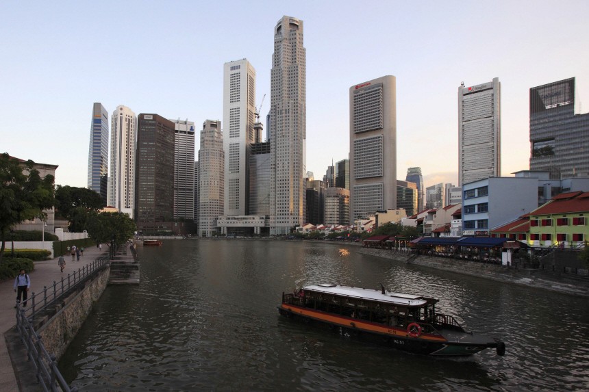 A tour boat travels up Singapore River past the skyscrapers of the financial district in Singapore