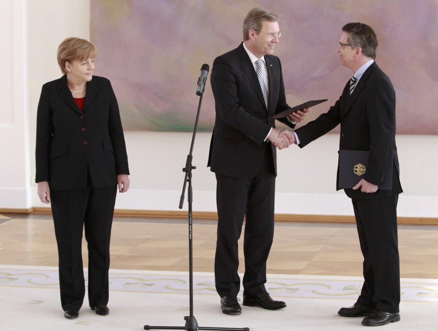 German Chancellor Merkel watches as President Wulff hands over the credentials of Defence Minister to former Interior Minister de Maiziere during a ceremony in presidential residence Bellevue palace in Berlin