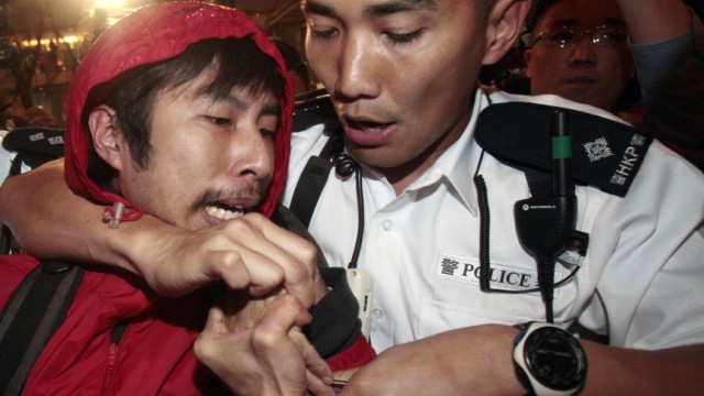Policemen remove a protester during a sit in protest against the annual budget along Des Voeux Road in Hong Kong