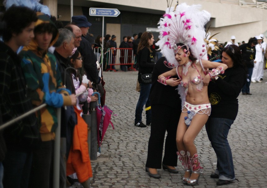 A samba dancer is helped with her dress before the start of a samba parade during the carnival in Sesimbra village