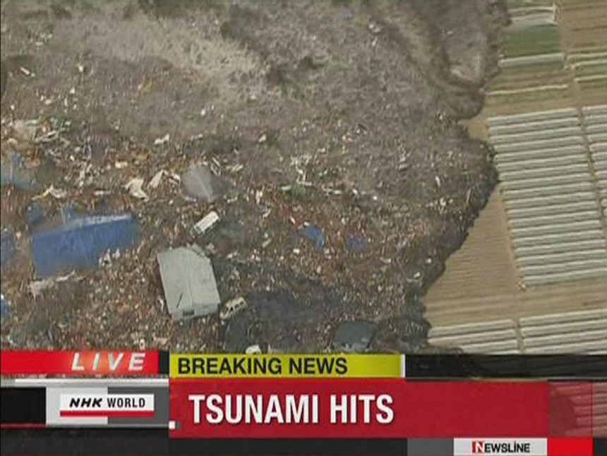 Frame grab of a tsunami carryings buildings across water in Sendai