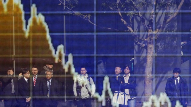 People are reflected on an electronic board displaying a graph showing the movement of the Japanese Yen's exchange rate against the U.S. dollar, outside a brokerage in Tokyo