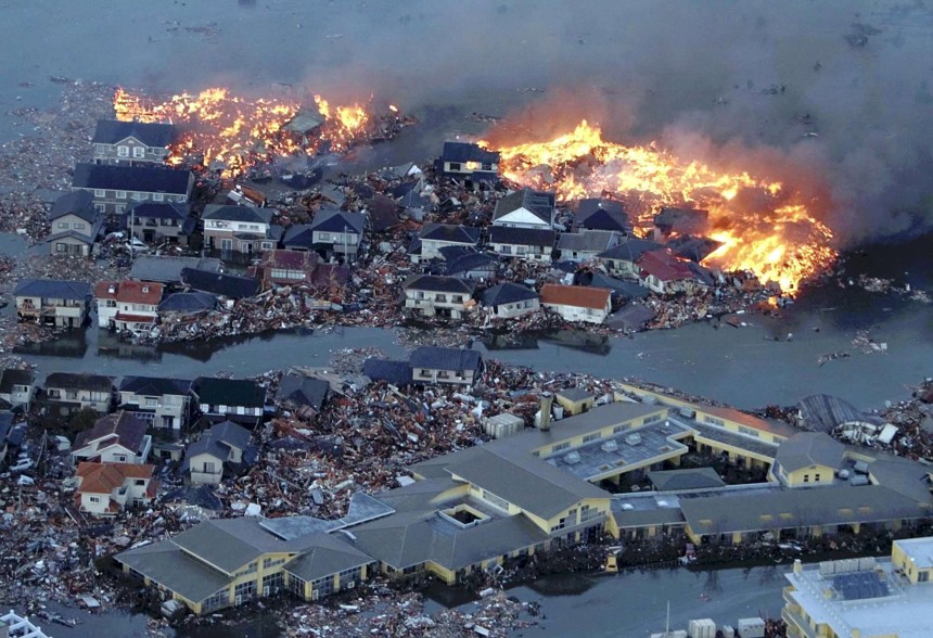 Houses swept out to sea burn following a tsunami and earthquake in Natori