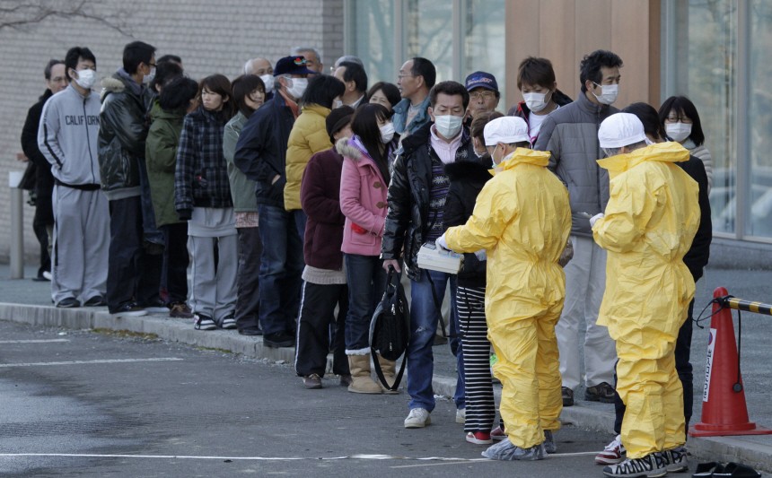 People queue to be screened by a technician in protective gear for signs of possible radiation in Nihonmatsu, northern Japan