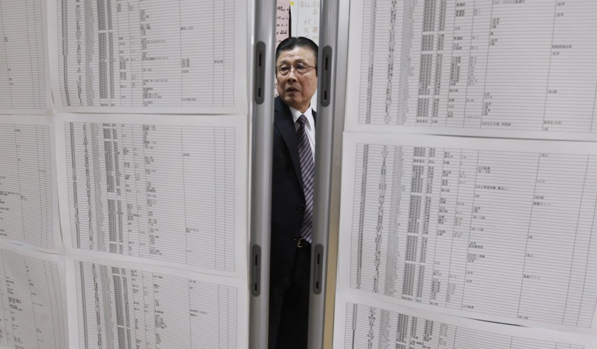 A man seeking for his relatives looks at a list of survivors at a shelter after an earthquake and tsunami in Rikuzentakata