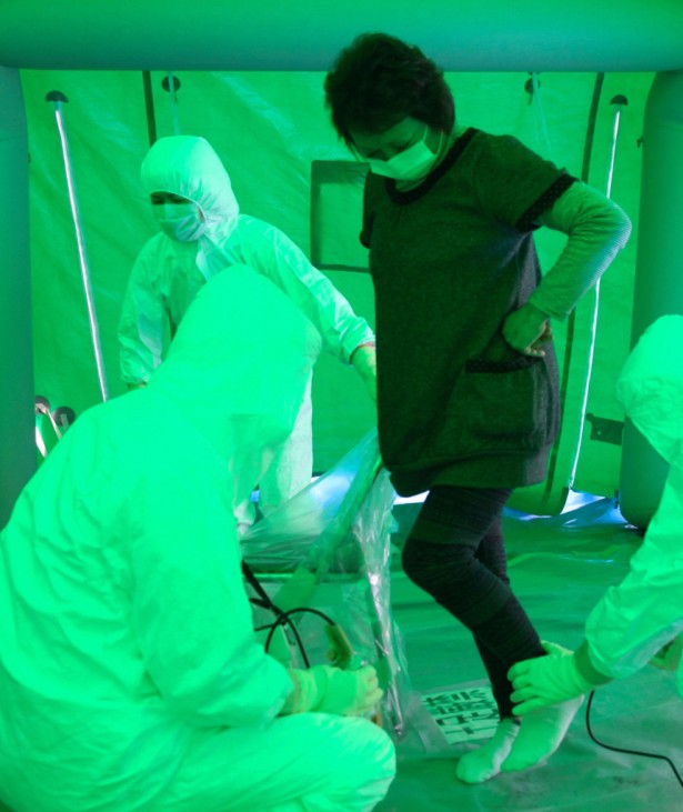 Medical staff use a Geiger counter to screen a woman for possible radiation exposure at a public welfare centre in Hitachi City