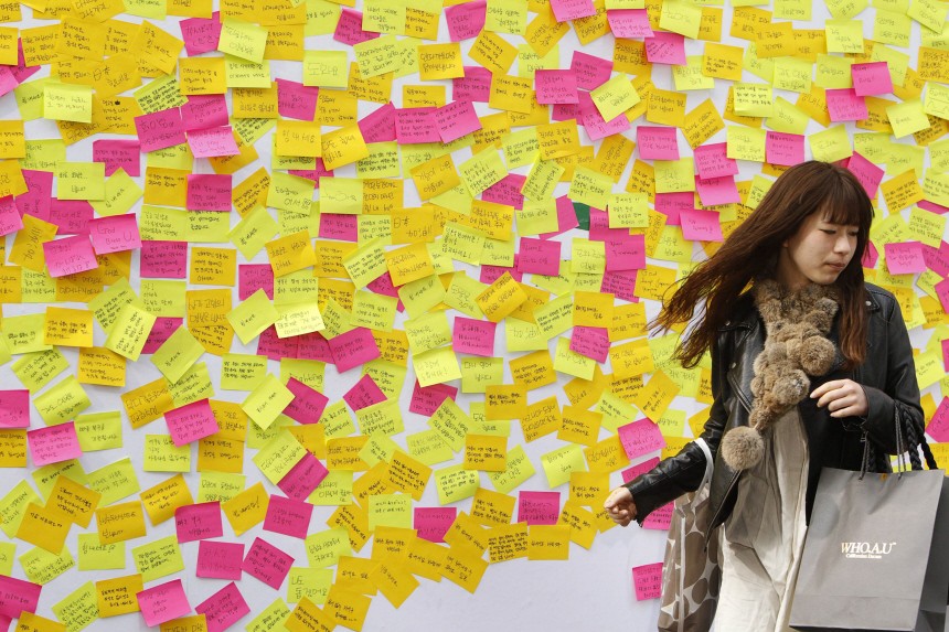 A woman walks away from a message wall after writing a message to the victims of last week's earthquake and tsunami in Japan in central Seoul