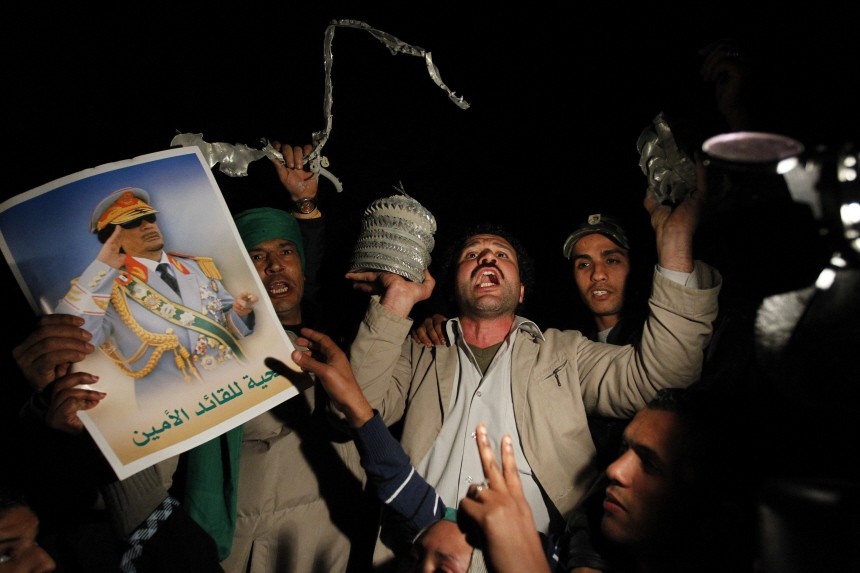 Supporters of Libya's leader Muammar Gaddafi show pieces of shrapnel from what the government said was a western missile attack on a building inside Bab Al-Aziziyah