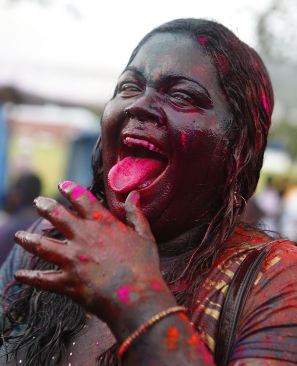 A woman covered with coloured powder called abeer laughs during Phagwa celebrations at the Savannah in Arranguez