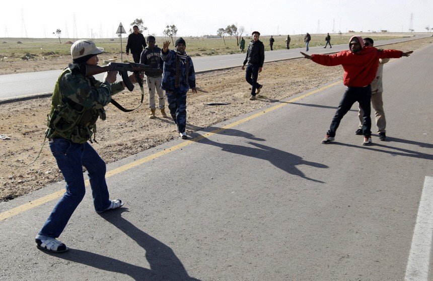 Rebel fighter points his gun at suspected Gaddafi supporter as other rebels try to protect suspected supporter, on road between Benghazi and Ajdabiyah, near Ajdabiyah