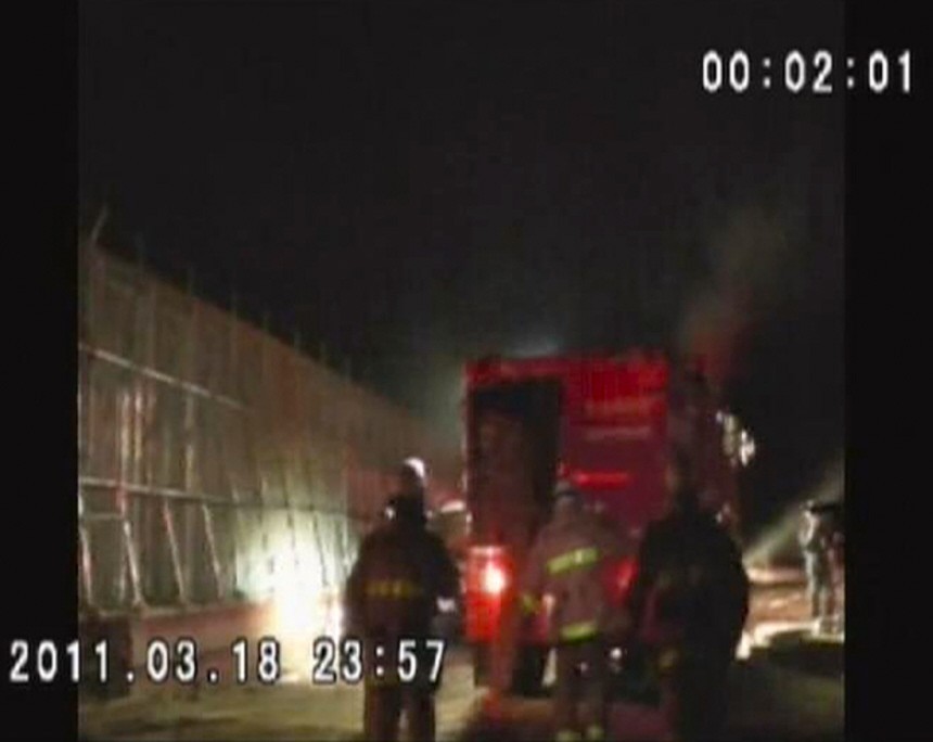 Firefighters wearing respirators work at the Fukushima nuclear plant in this still image taken from video