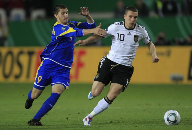 Germany's Podolski is challenged by Kazakhstan's Khizhnichenko during their Euro 2012 Group A qualifying soccer match in Kaiserslautern