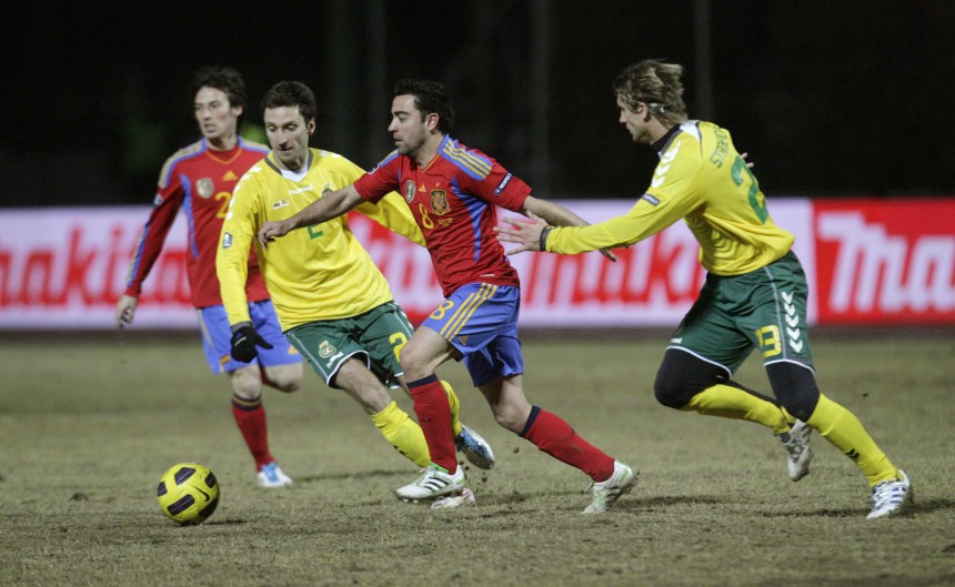 Xavi of Spain fights for the ball with Semberas and Stankevicius of Lithuania during their Euro 2012 qualifying soccer match in Kaunas