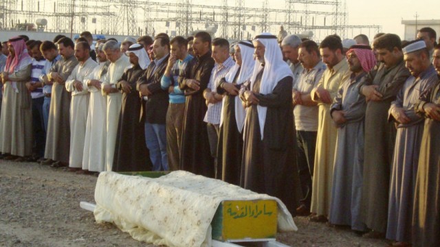 Residents pray over the coffin of Iraqi journalist Sabah al-Bazee before his burial at a cemetery in Samarra