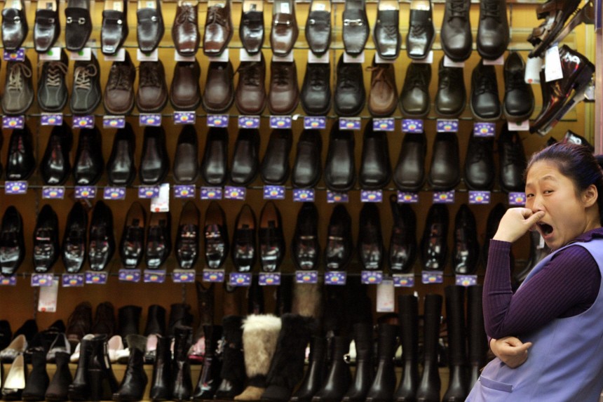 Chinese shopkeeper yawns while waiting for customers at shoe store in Beijing