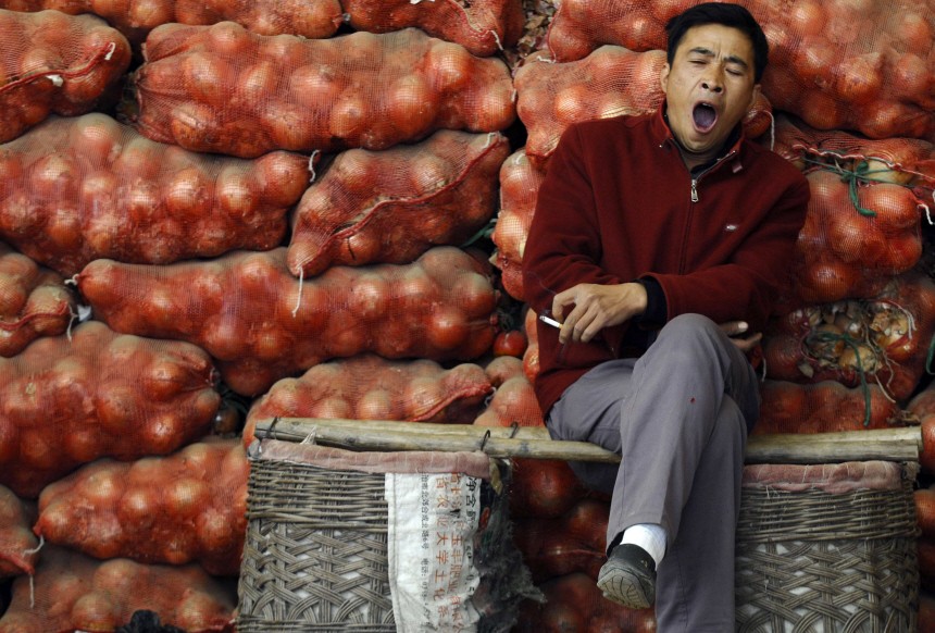 Vendor yawns while waiting for customers at his stall at vegetable market in Changzhi