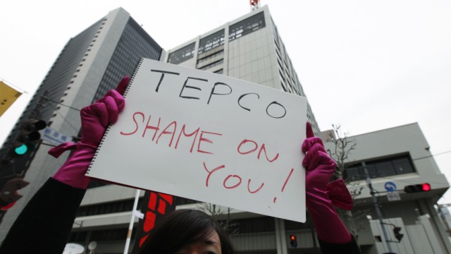 An anti-nuclear protester holds a sign in front of TEPCO's headquarters in Tokyo